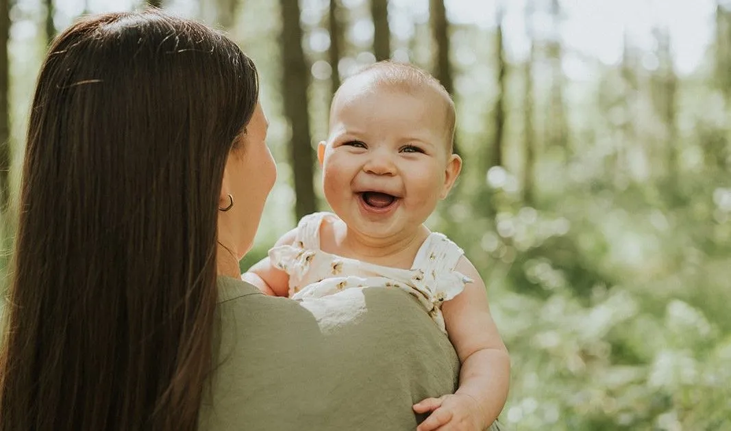 Mama met een lachende baby op de arm in het groen