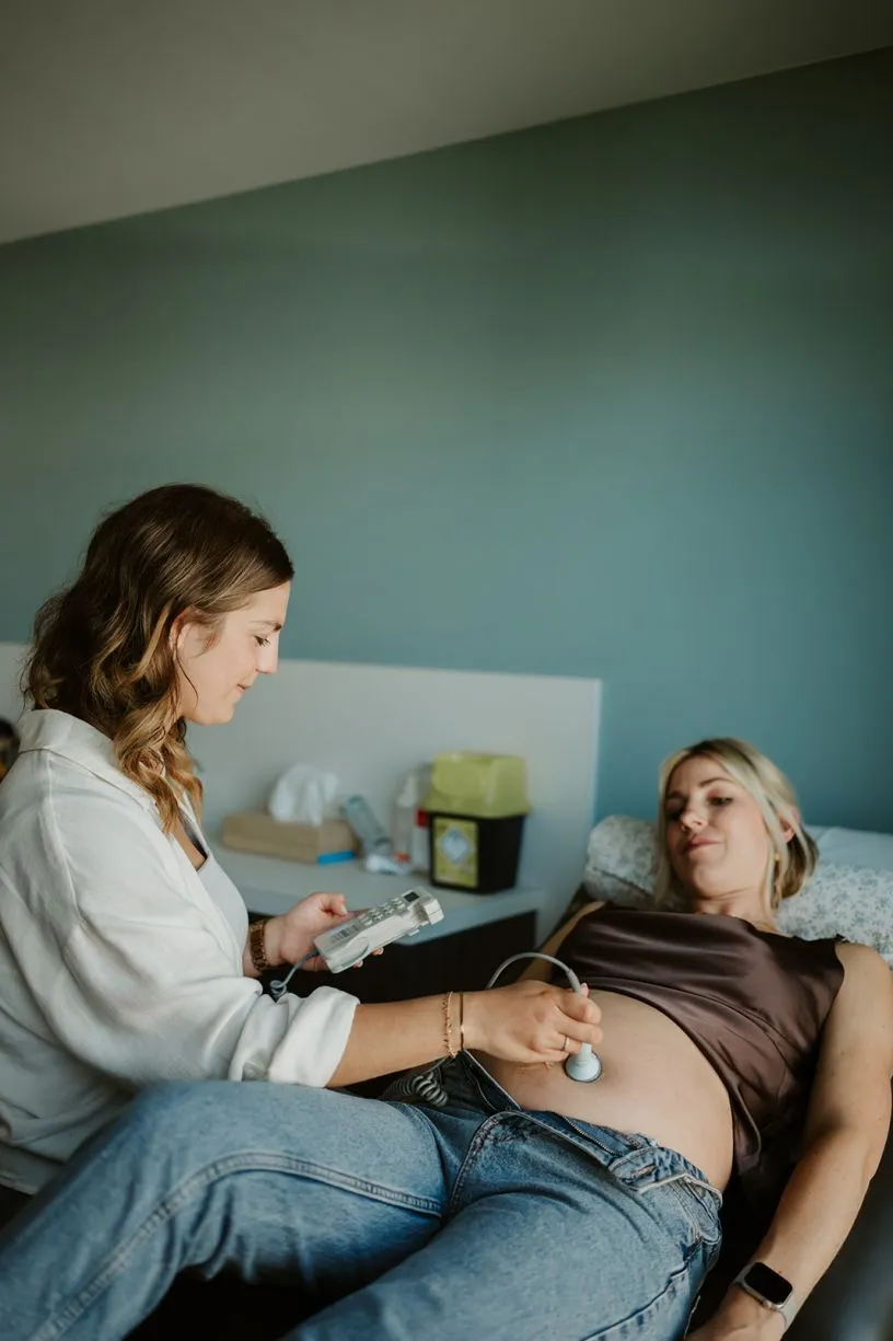 Vroedvrouw luistert naar de harttonen van de baby bij een zwangere vrouw